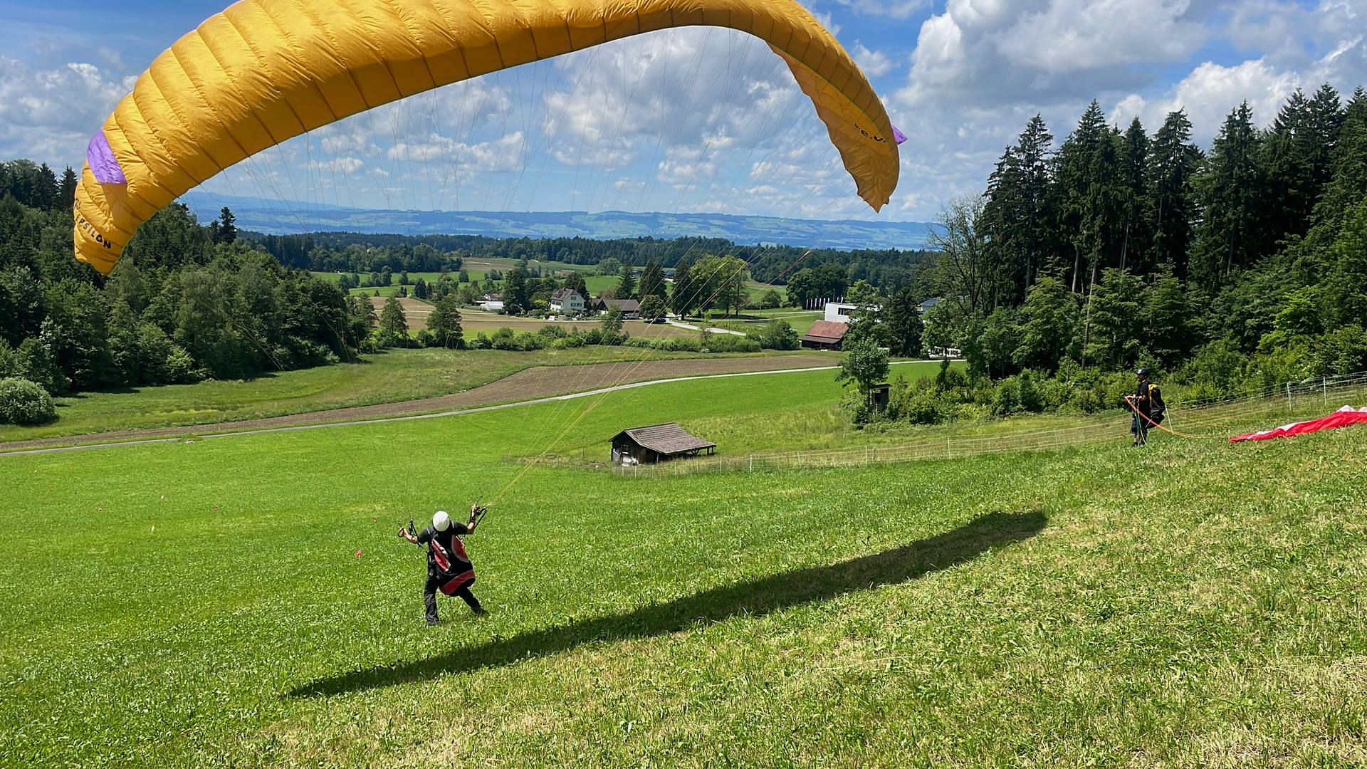 Ein Kursteilnehmer zieht am Übungshang den Gleitschirm kontrolliert auf und achtet dabei auf den nötigen Impuls und auf Symmetrie.