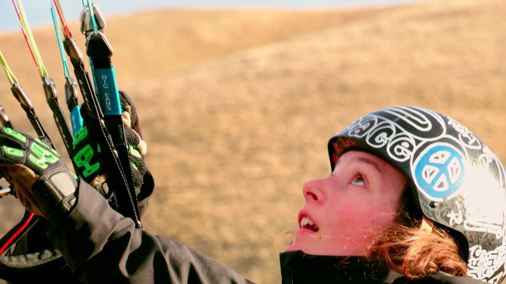 gleitschirm-groundhandling-schueler-konzentriert-quer Eine Flugschülerin beim eingedrehten Spielen mit dem Gleitschirm, wobei sie ständig ihre Position am Boden der Schirmposition anpasst.