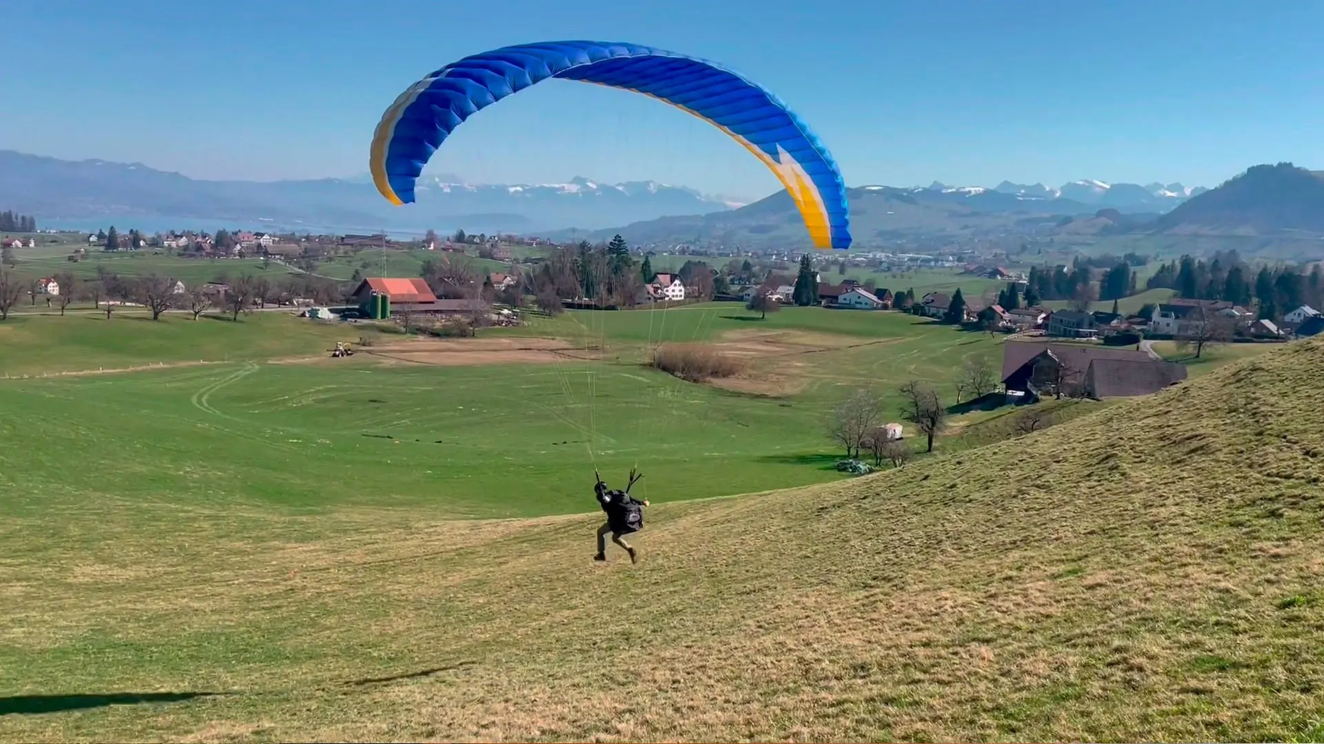 gleitschirm-grundkurs-flugschueler-abgehoben-uebungshang-quer Ein Flugschüler hebt mit entschlossenen Schritten zu einem kurzen Flug am Übungshang ab.