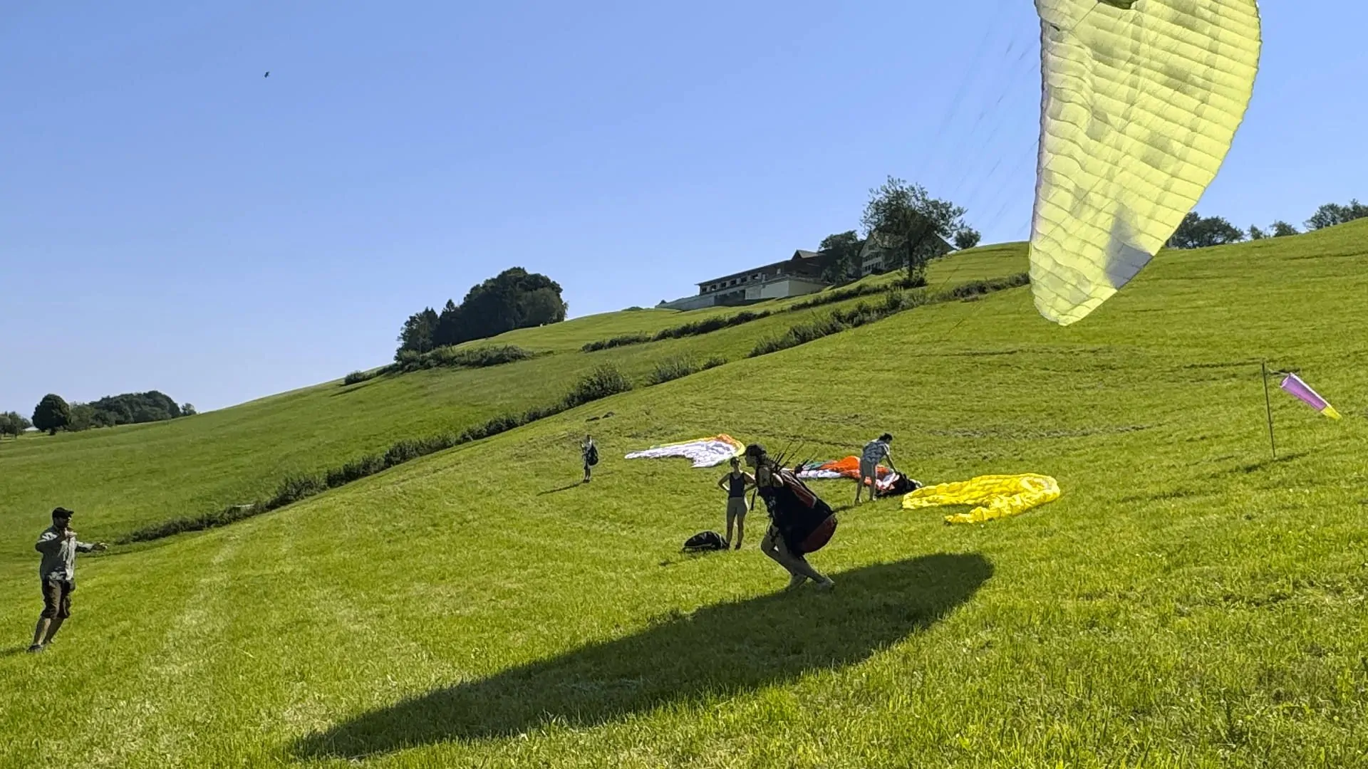gleitschirm-schnuppertag-aufziehen-uebungshang-quer Erstes beherztes Aufziehen mit genügend Körpervorlage einer Teilnehmerin beim Gleitschirm-Schnuppertag gemäss Anweisungen des Fluglehrers.