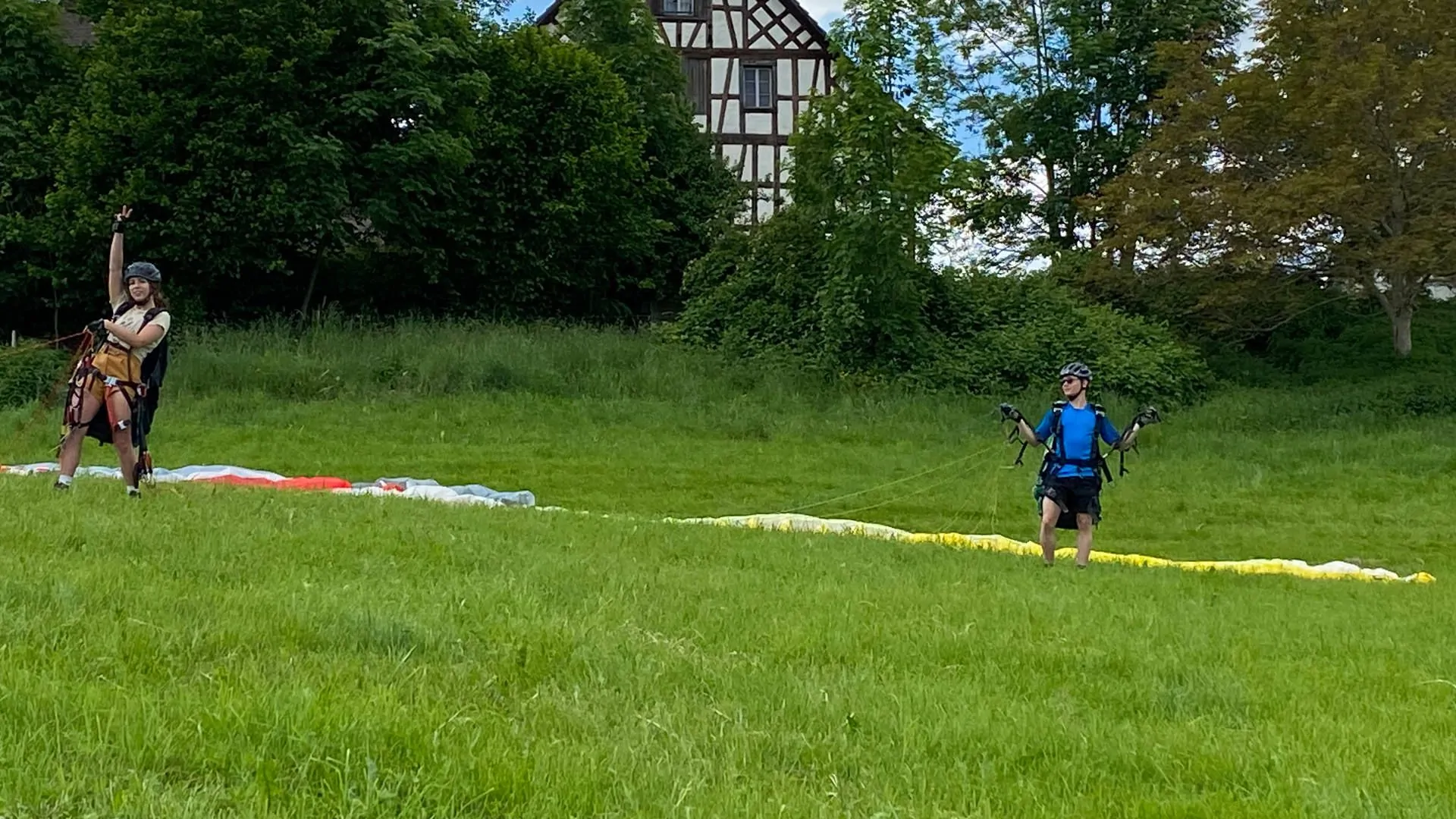 Zwei Teilnehmer beim Gleitschirm-Schnuppertag machen sich startklar und geben per Handzeichen zu erkennen, dass sie für eine Übung bereit sind.