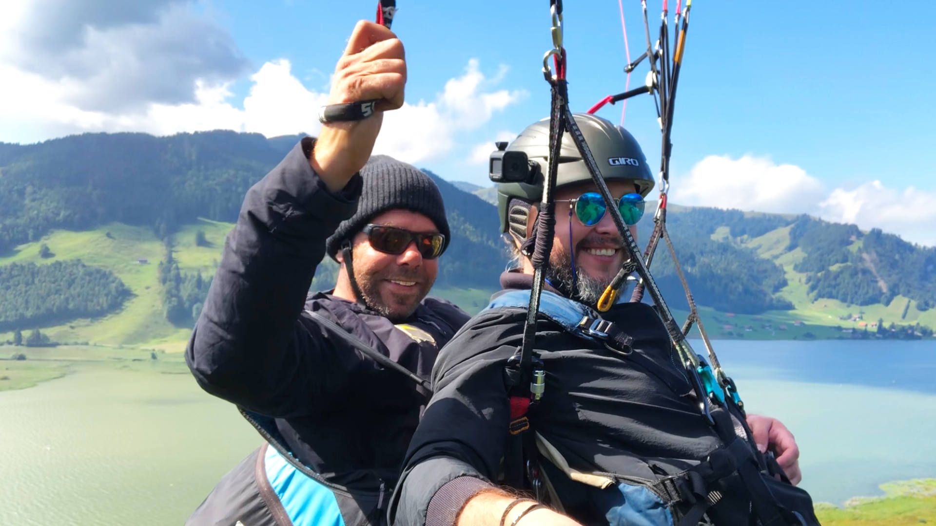 gleitschirm-tandemflug-sommer-selfie-euthal-einsiedeln-quer Flugaufnahme: Selfie von Pilot und Passagier bei einem Gleitschirm-Tandemflug in Euthal am Sihlsee im Spätsommer.