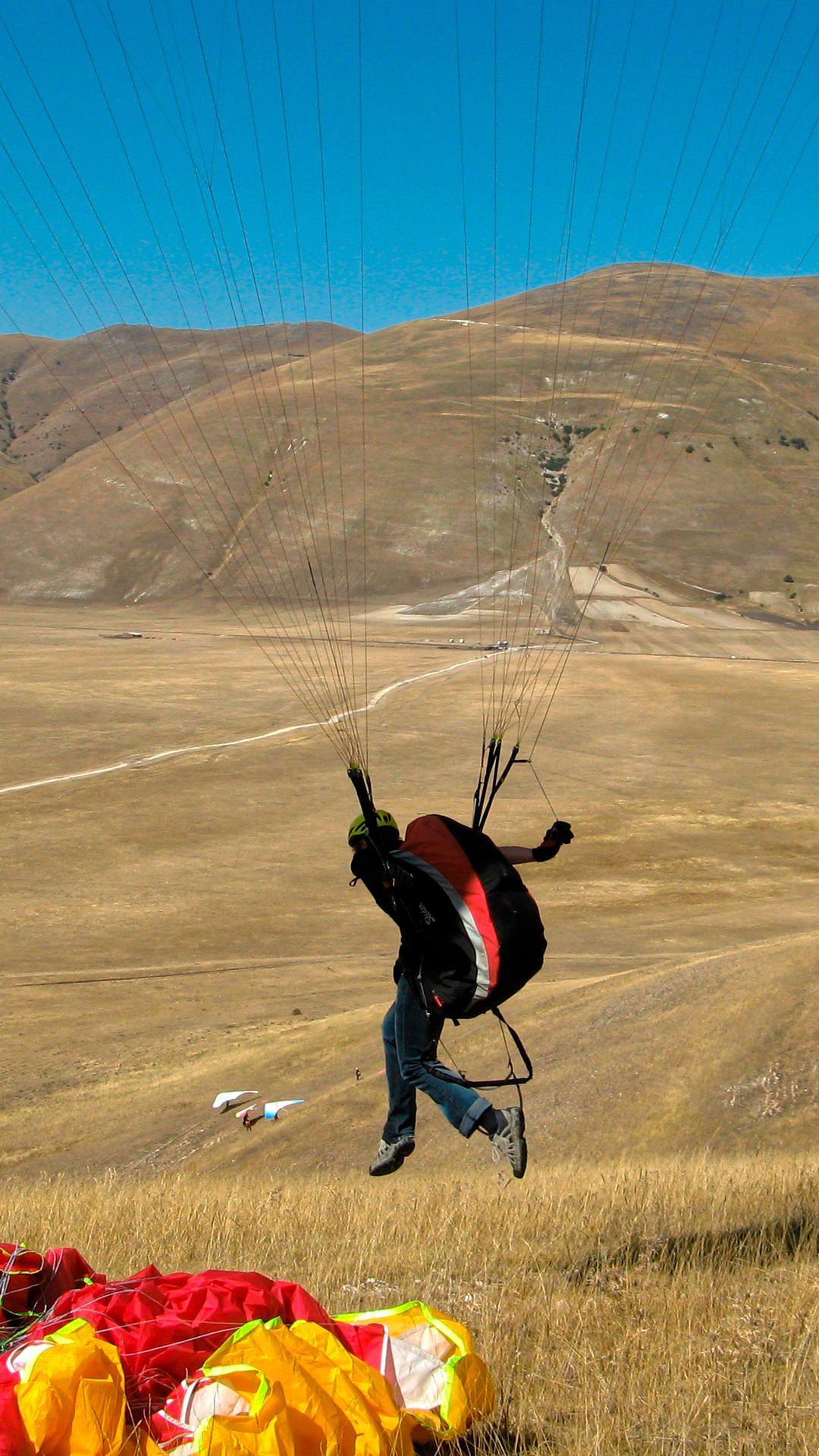 Ein Pilot hebt am Übungshang mit dem Gleitschirm ab und gleitet noch in aufrechter Position bodennah in den freien Luftraum.