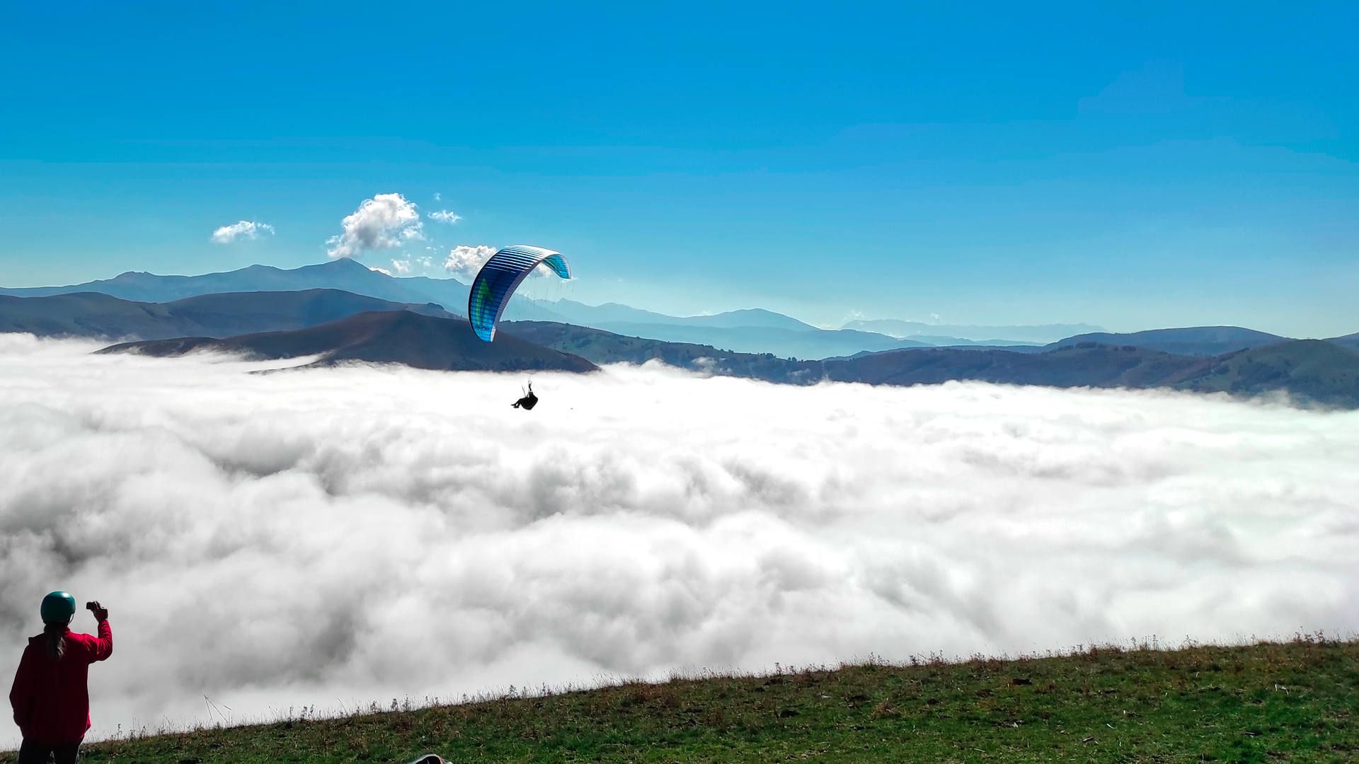Ein Gleitschirmpilot fliegt über dem morgendlichen Nebelmeer vom Monte Veletta und kann sich im thermischen Aufwind über Startplatzhöhe halten.