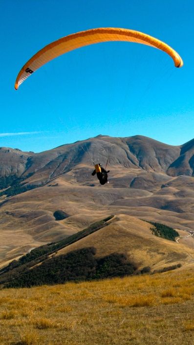 Ein Pilot setzt mit seinem Gleitschirm am Monte Veletta aus passender Höhe zu einer Landung an.