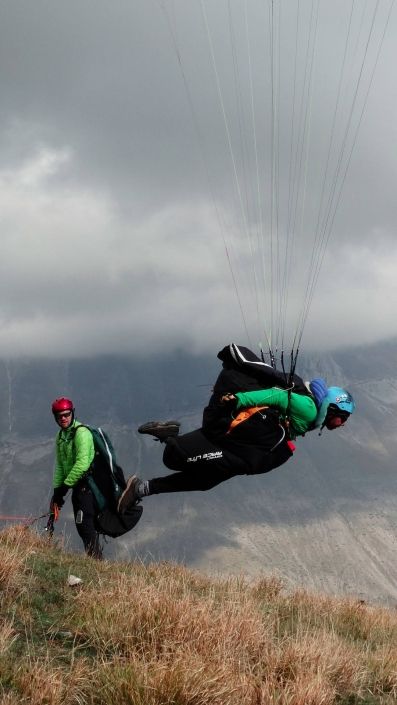 Entschlossene Beschleunigungsphase beim Start eines Gleitschirmpiloten mit sehr viel Körpervorlage.