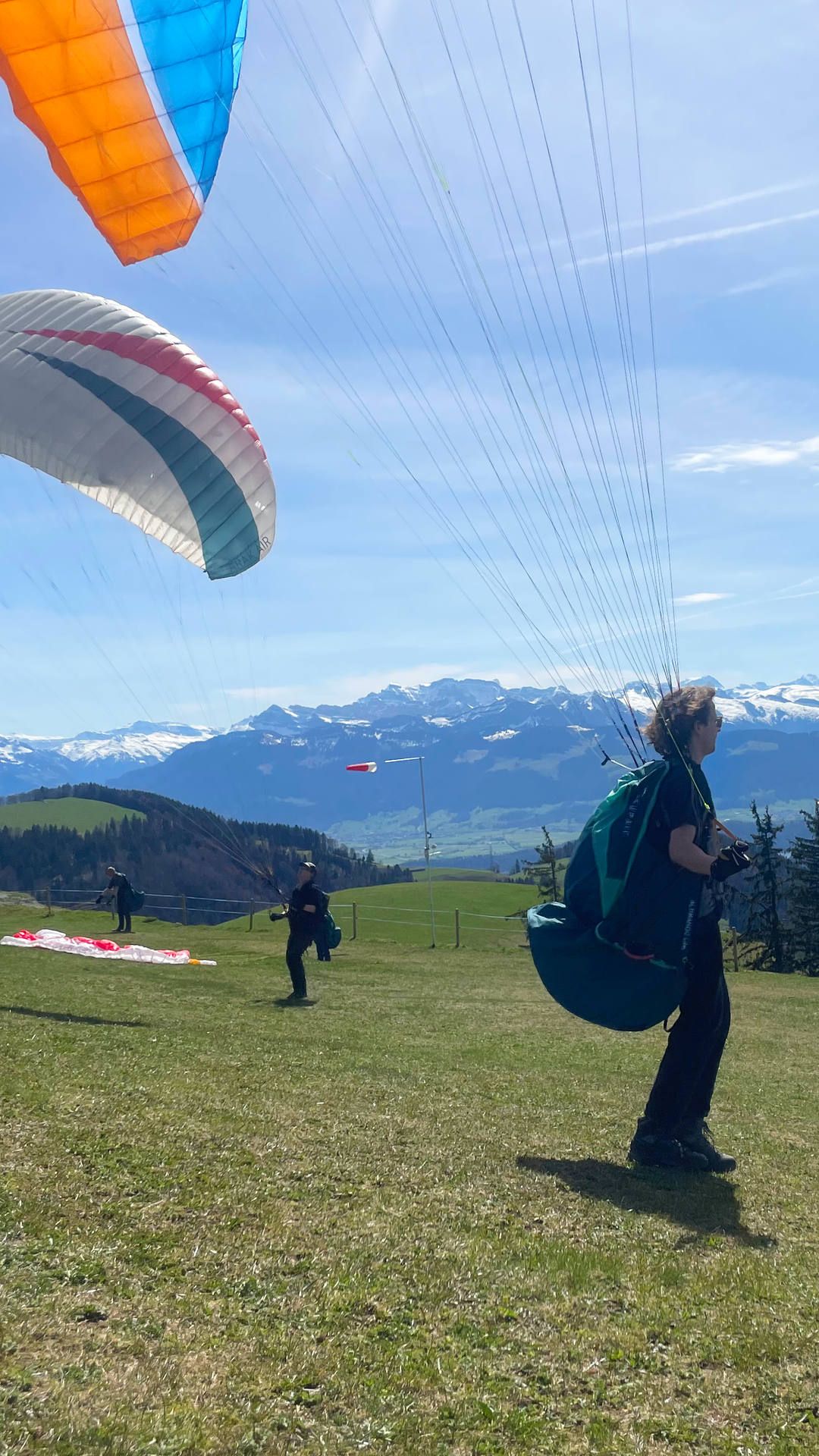 groundhandling-fruehling-schirmkontrolle-alp-scheidegg-hoch Auf der Alp Scheidegg im Zürcher Oberland vertreiben sich Gleitschirmpiloten die Zeit mit Groundhandling bis zuverlässige Thermik einsetzt.